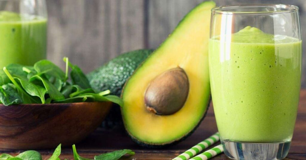 Abacate maduro cortado ao meio, mostrando sua polpa verde e textura cremosa, ao lado de torradas e guacamole