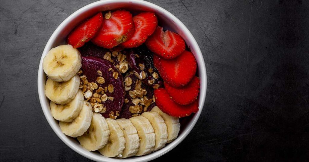 Criança saboreando açaí em uma tigela colorida com frutas
