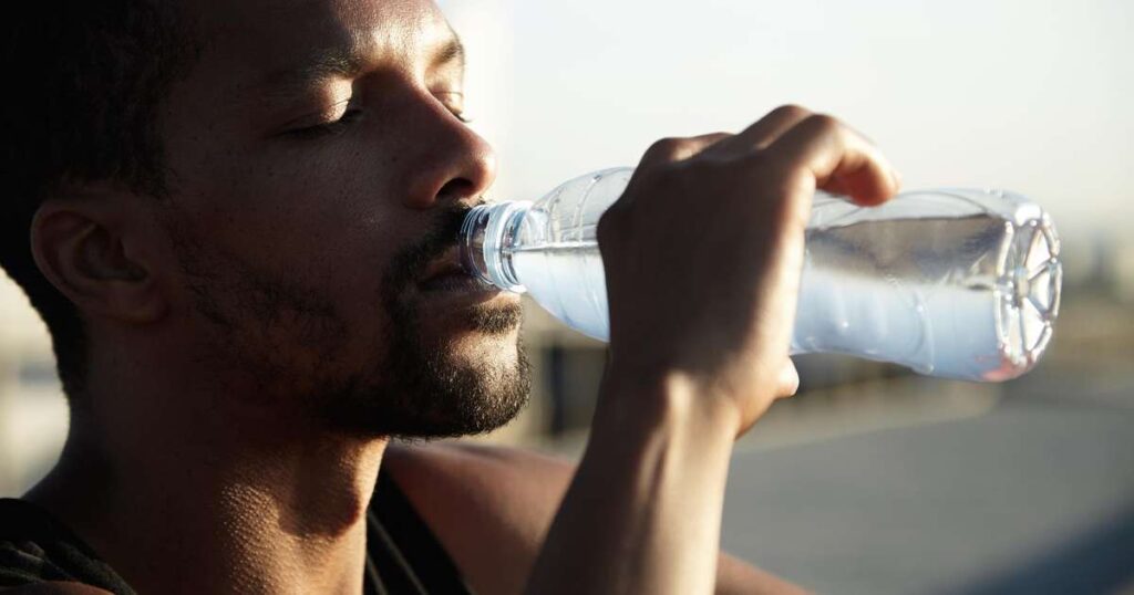 Hidratação consciente: copo de água ao lado de frutas e vegetais