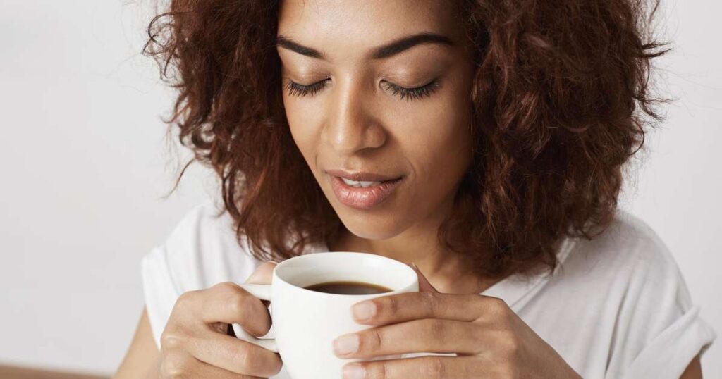 Uma xícara de café quente sobre uma mesa ao lado de uma fatia de pão integral