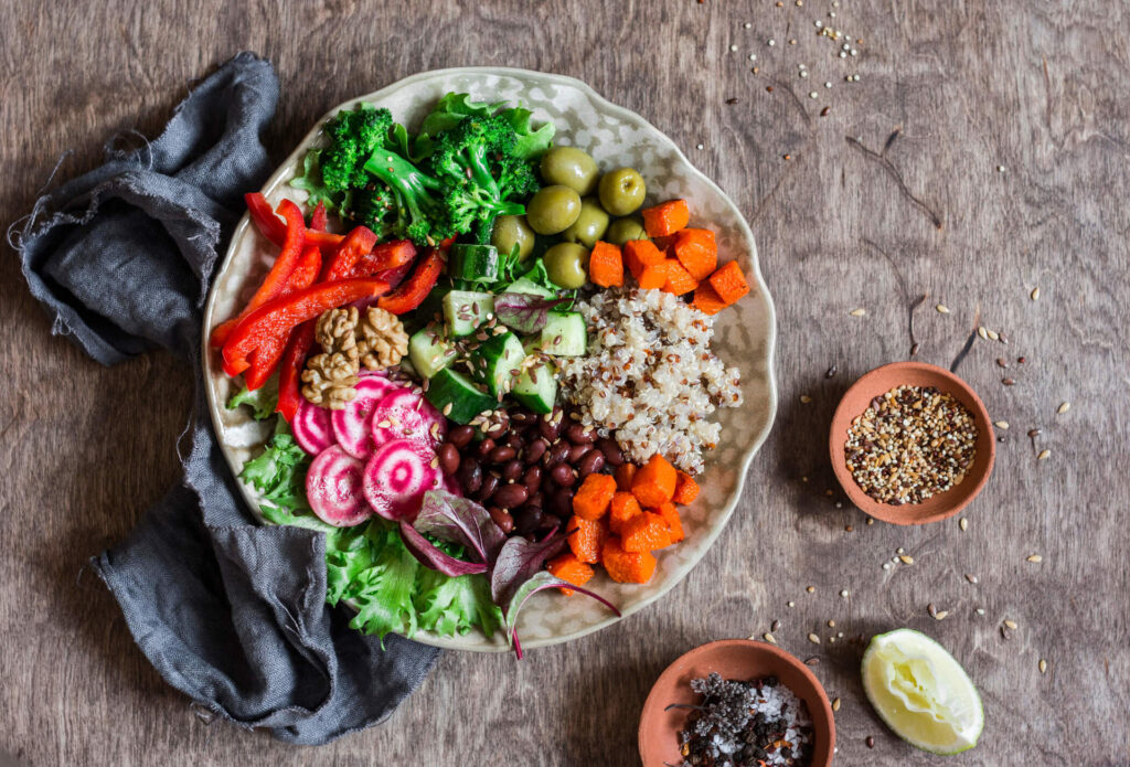 Prato colorido com alimentos de origem vegetal, incluindo frutas, legumes e grãos integrais, representando a dieta plant-based.