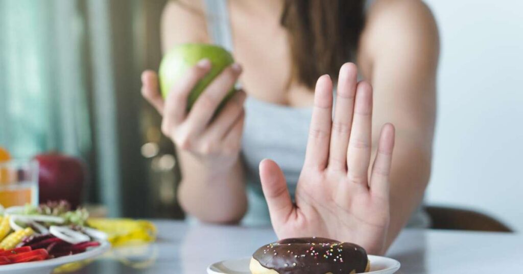 Uma mão segurando um pedaço de açúcar ao lado de frutas frescas